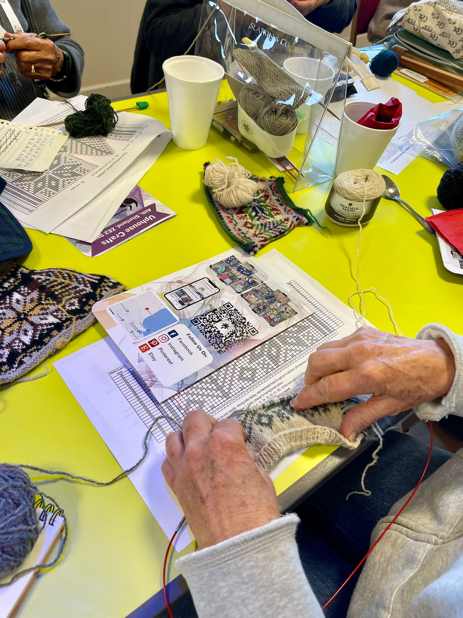 Knitting hands at desk with yarn and pattern