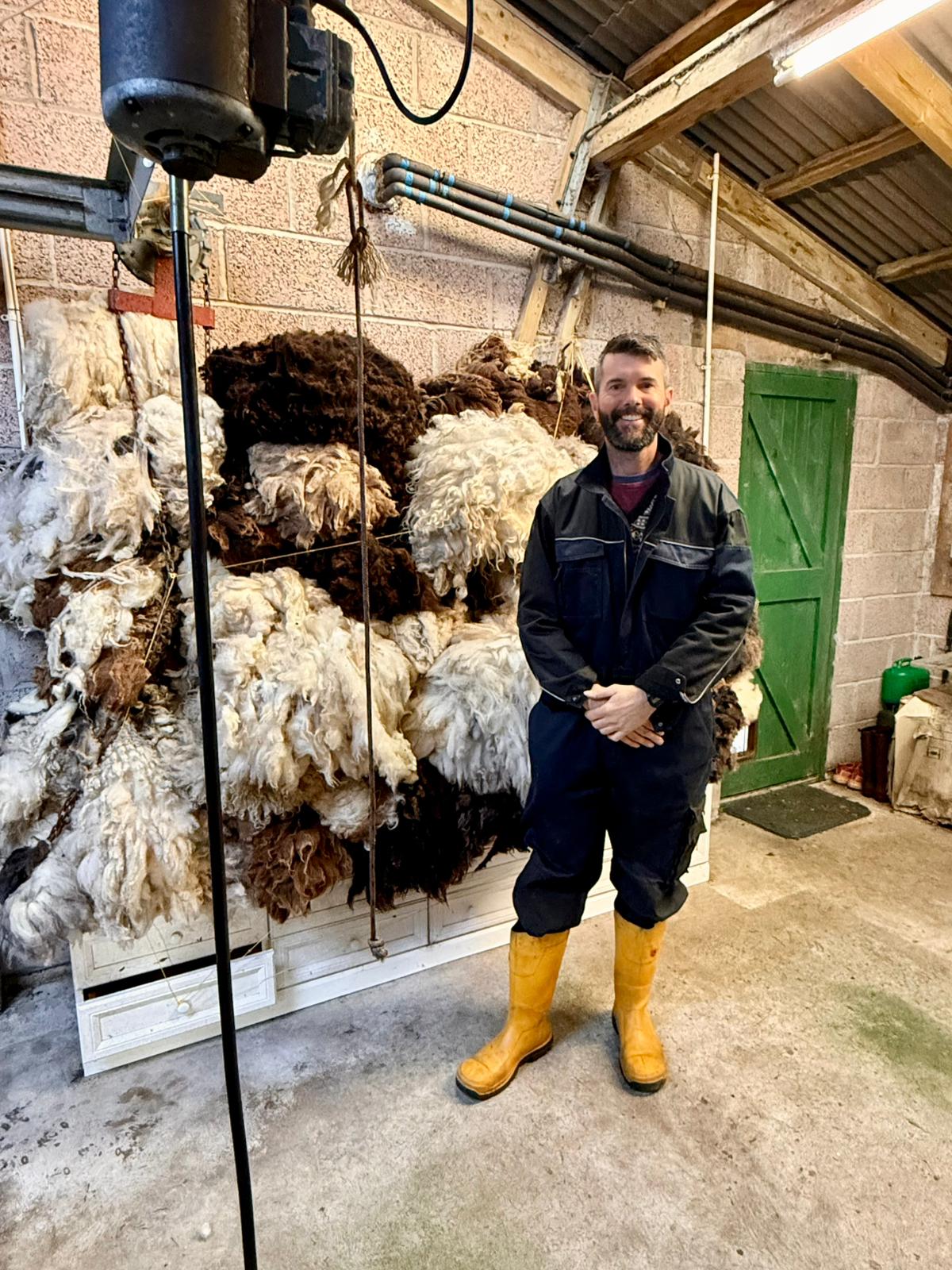 Man in front of sheep fleeces