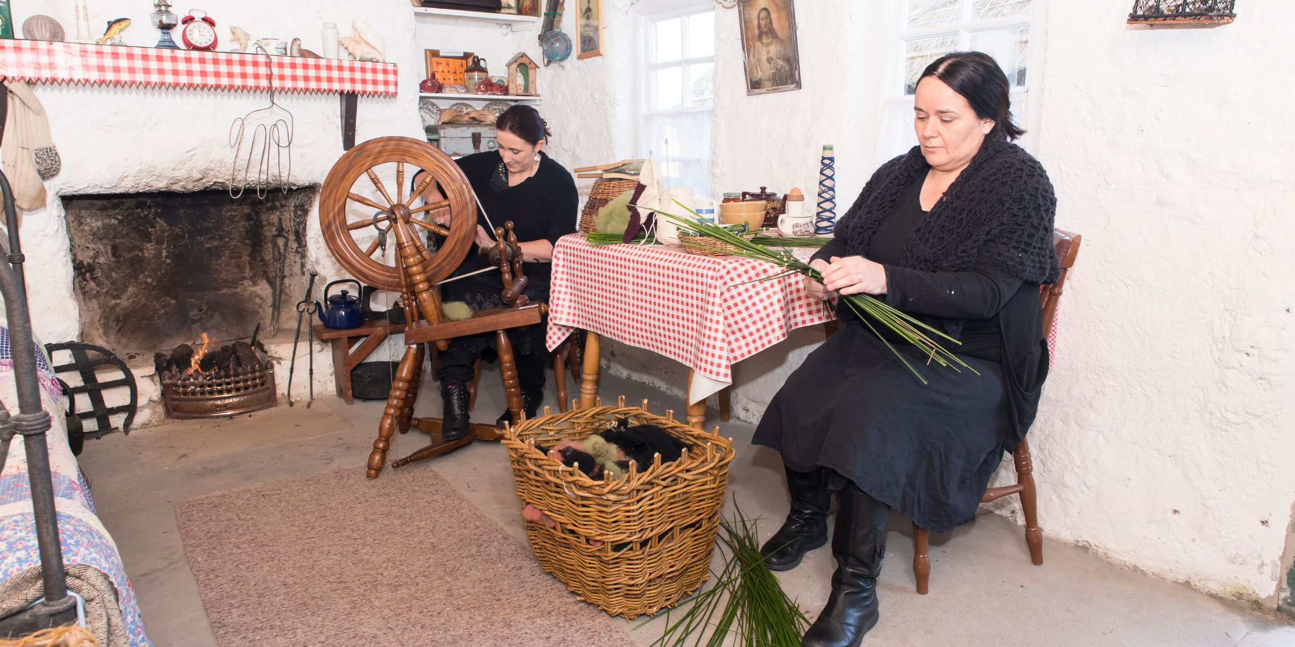 Women demonstrating traditional Irish spinning and basket weaving inside a restored Irish cottage, showcasing Ireland's rich textile and craft heritage.